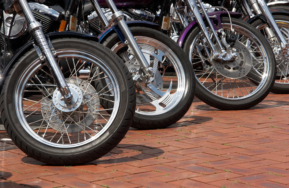 A line of motorcycles lined up with a focus on their front tyres.