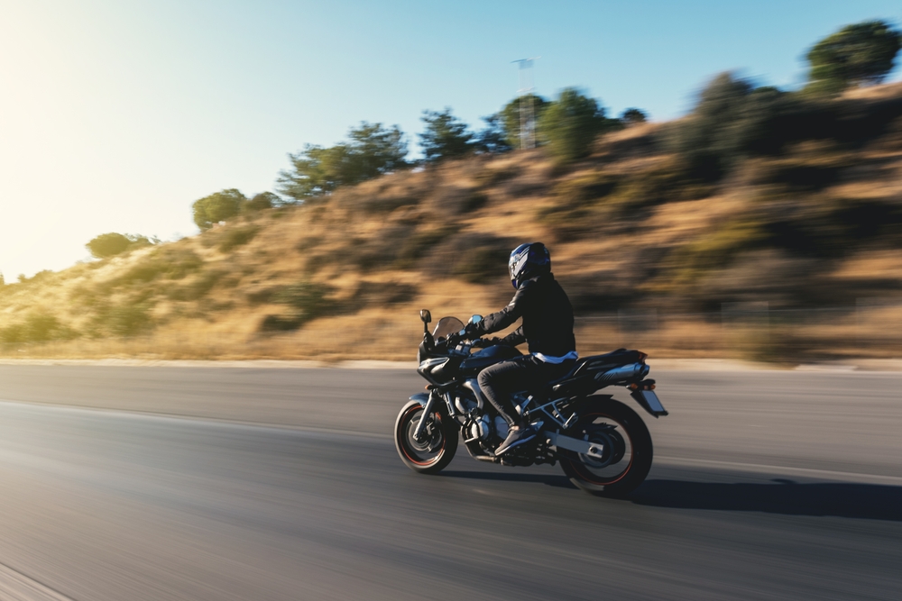 A rider zooming along a road on a motorcycle.