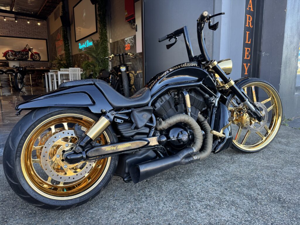 A black Harley Davidson with gold rims parked outside Taverner Motorsports workshop.