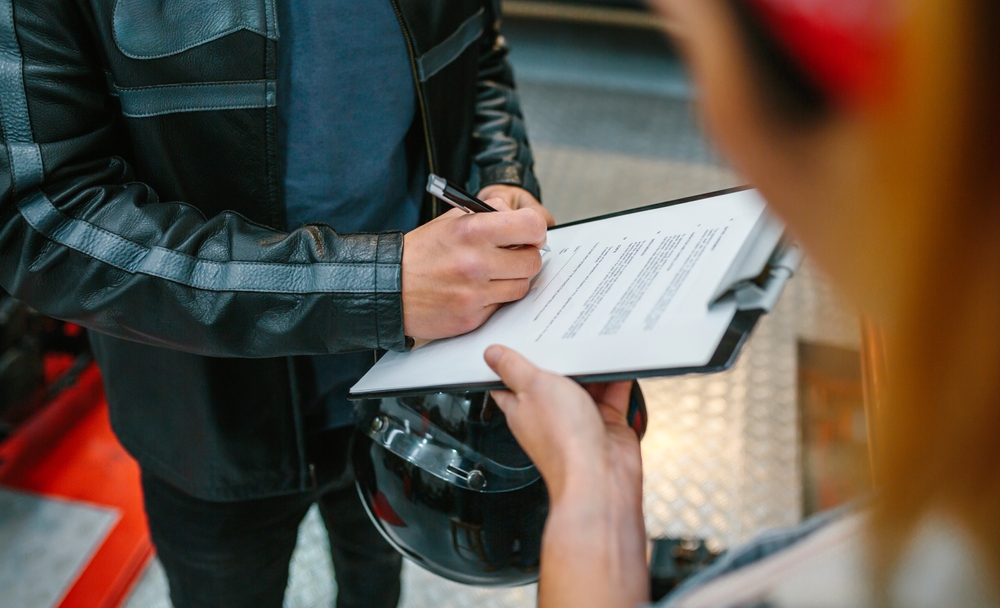 A motorcycle rider signing a form.